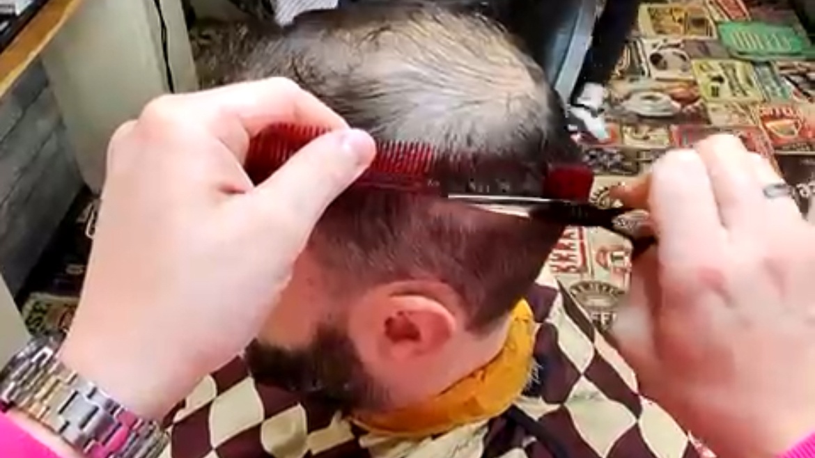 Barber cutting man's thinning hair